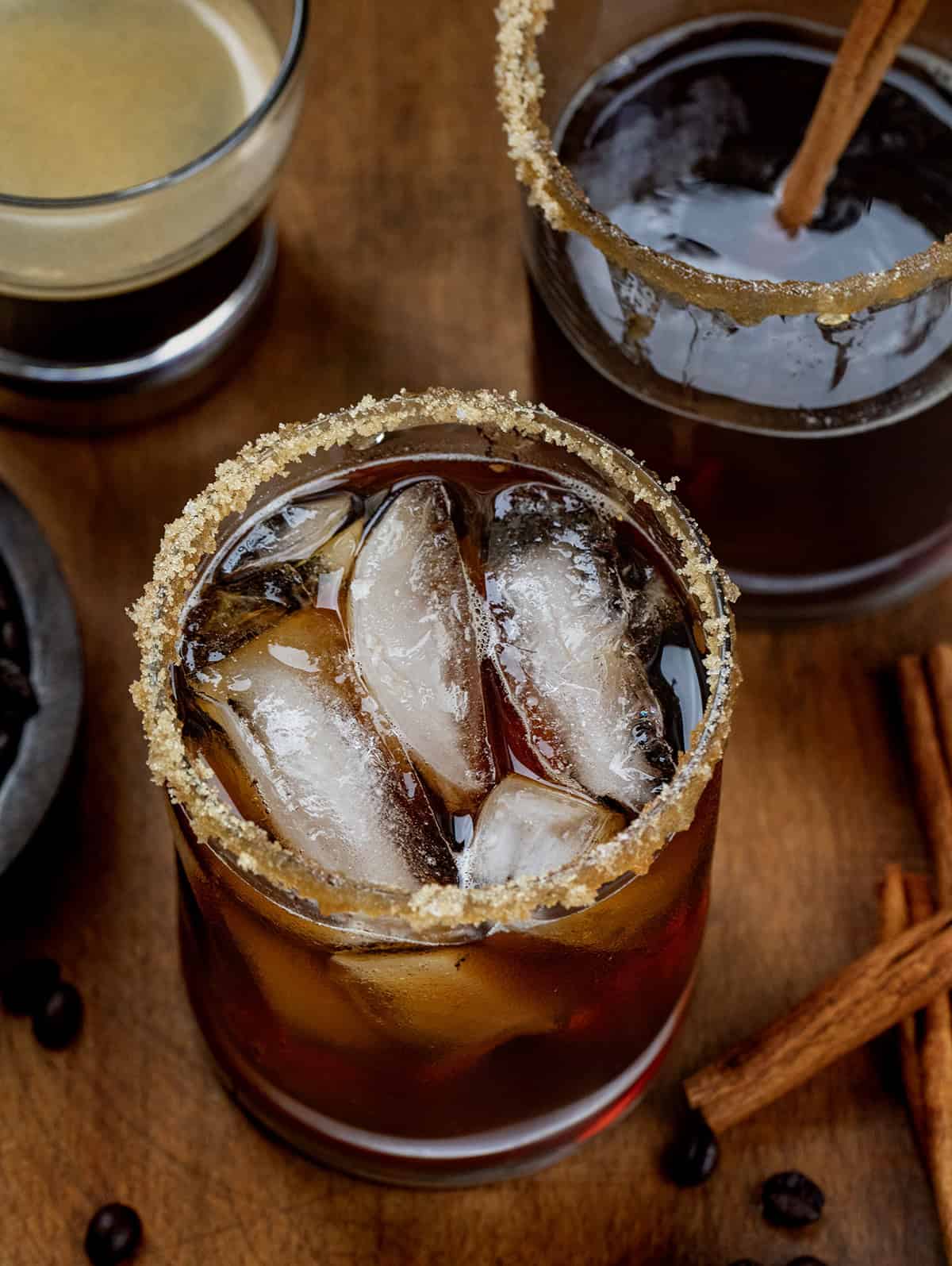 Glasses of Maple Bourbon Espresso on a wooden table with espresso and coffee beans Glasses of Maple Bourbon Espresso on a wooden table with espresso and coffee beans.