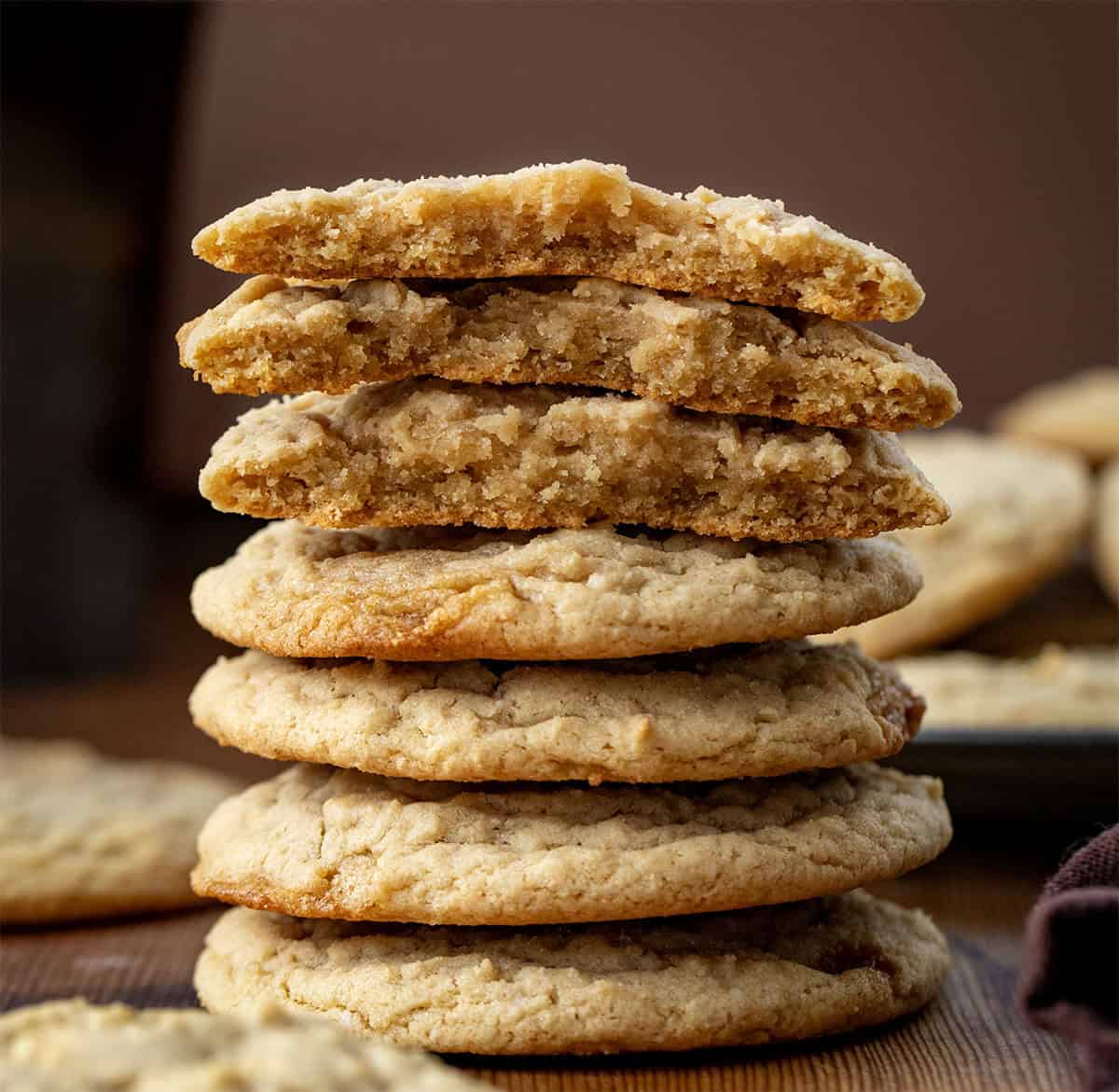 Stack of Maple Cookies with the top cookies broken showing inside texture on a wooden table.