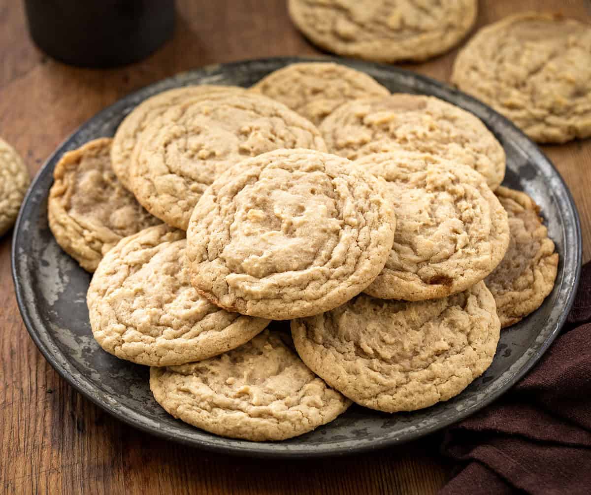 Plate of Maple Cookies on a wooden table with cookies around it.