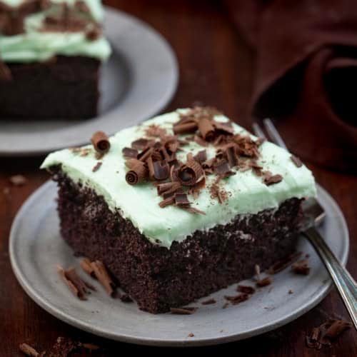 Pieces of Mint Chocolate Sheet Cake on plates on a wooden table.