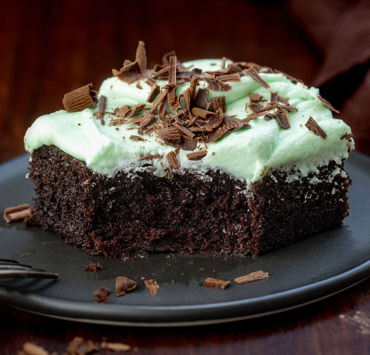 Piece of Mint Chocolate Sheet Cake with a bite taken out of it and a fork resting on the plate.