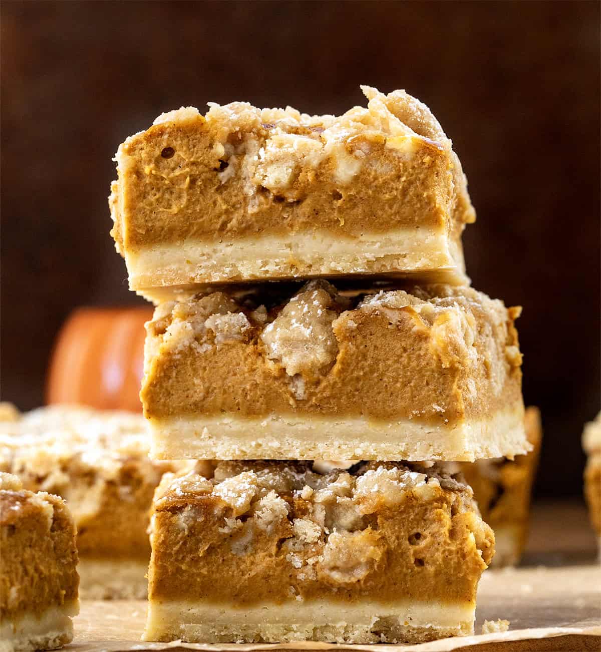 Stack of Pumpkin Cream Crumb Bars on a wooden table.