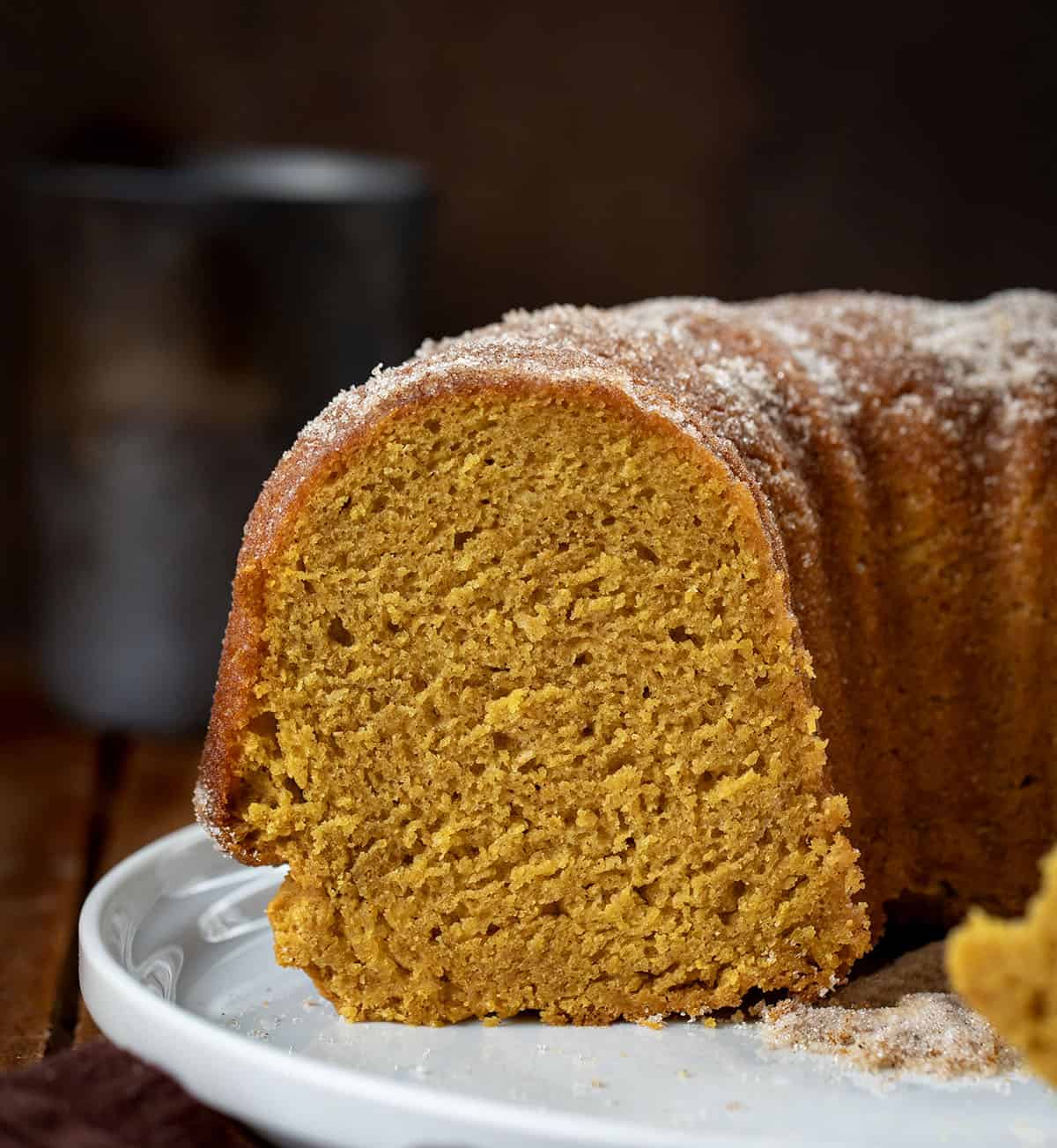Cut into Pumpkin Spice Donut Bundt Cake on a platter on a wooden table close up.