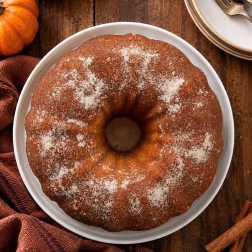 Pumpkin Spice Donut Bundt Cake on a white platter on a wooden table from overhead.