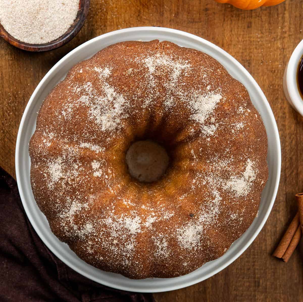 Pumpkin Spice Donut Bundt Cake on a white platter on a wooden table from overhead.
